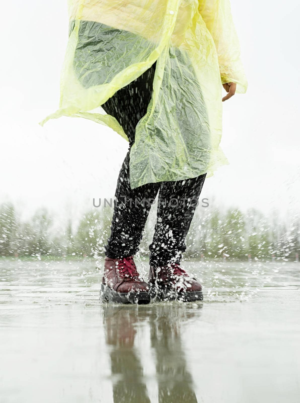 woman running on asphalt in rainy weather. Close up of legs and shoes splashing in puddles.