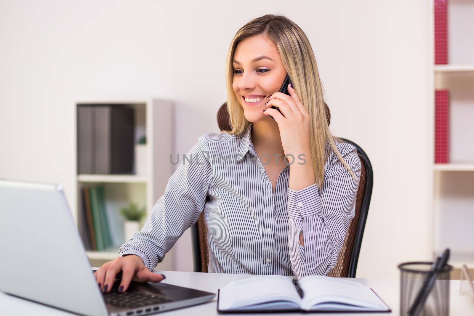 Businesswoman using mobile phone while working in her office.