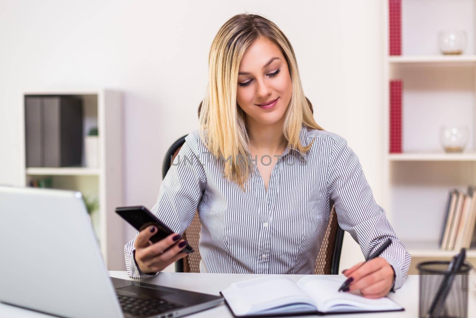 Businesswoman using mobile phone while working in her office.