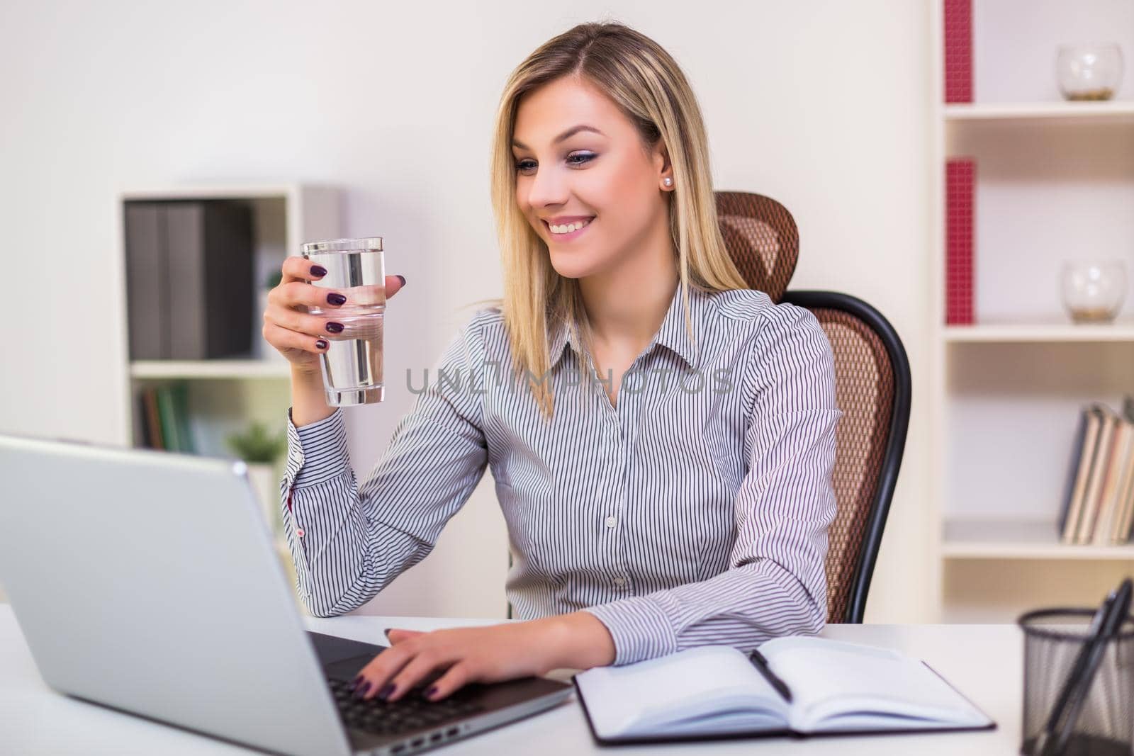 Businesswoman drinking water while working in her office.