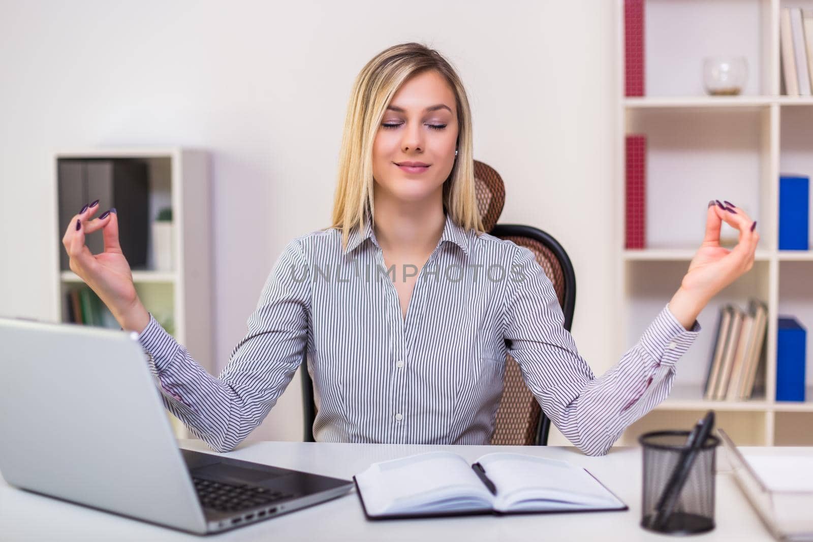 Businesswoman meditating in her office while working.