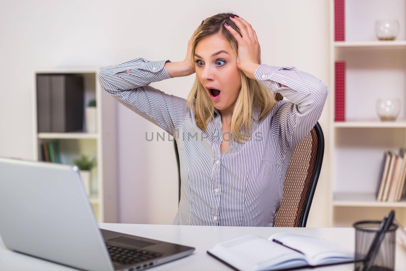 Businesswoman in panic looking at laptop while working in her office.