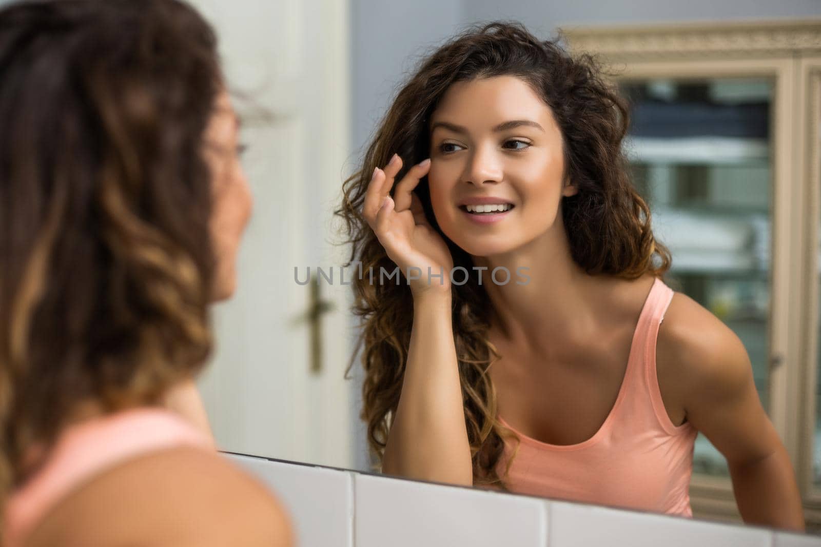 Beautiful woman looking herself in the mirror in her bathroom.