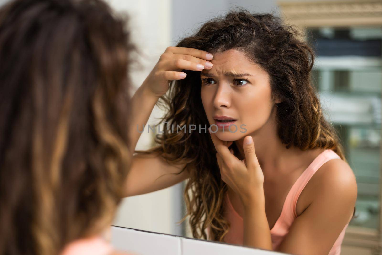 Worried woman is looking her first wrinkles in the bathroom.