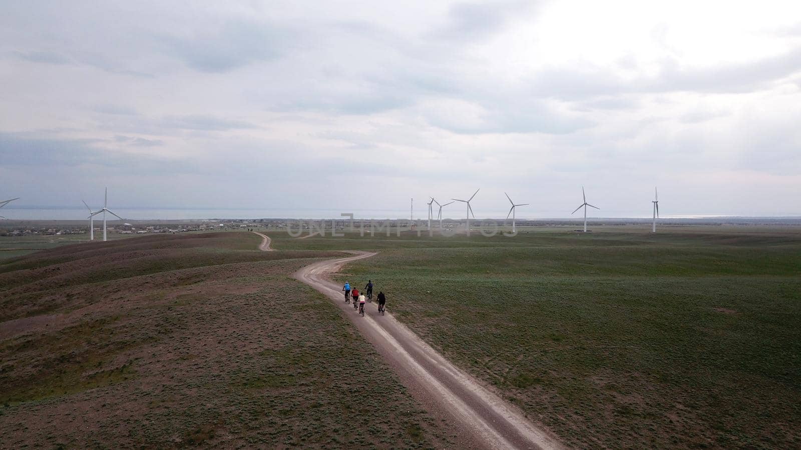 A group of cyclists rides along the windmills. by Passcal