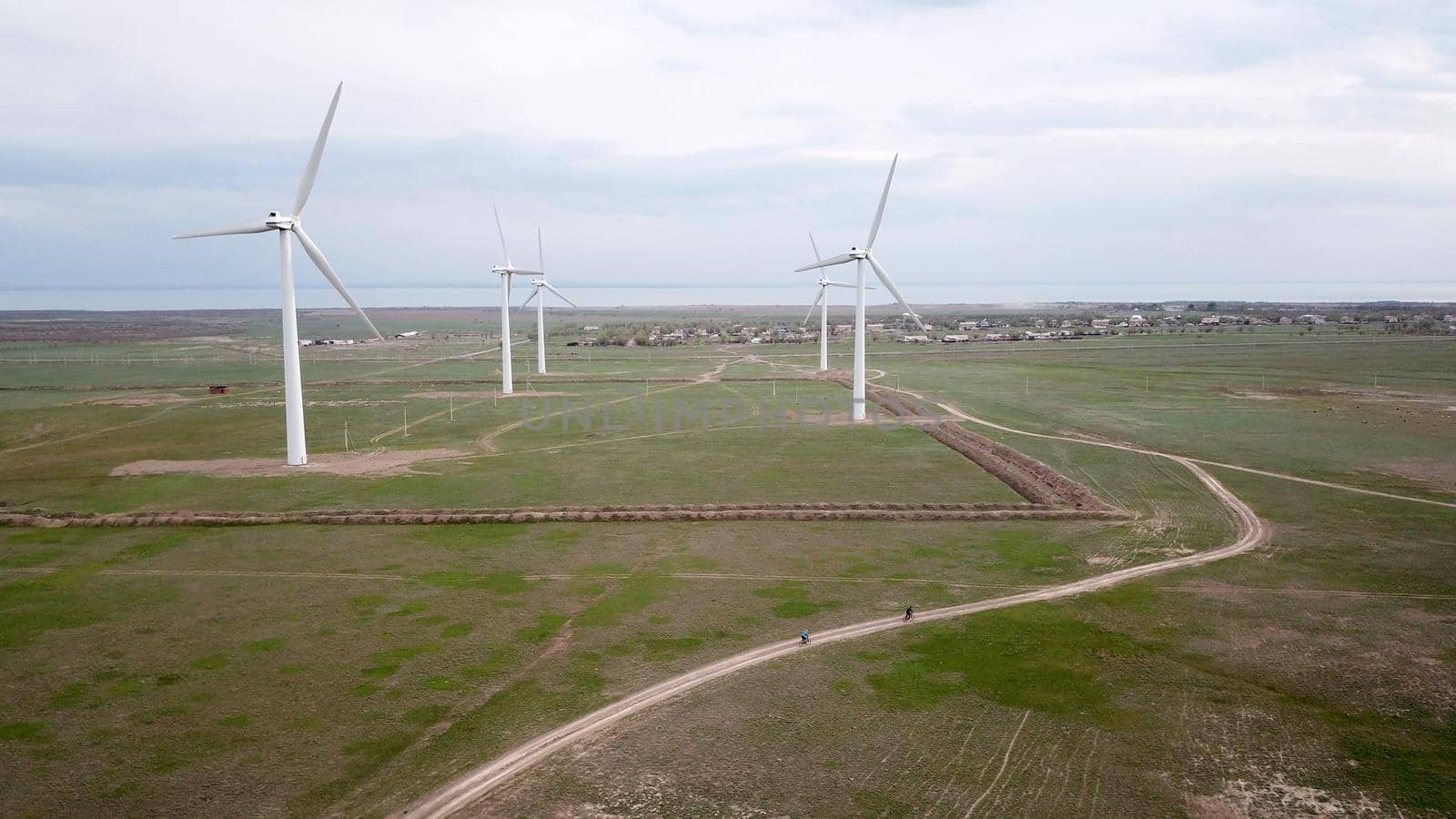 A group of cyclists rides along the windmills. by Passcal