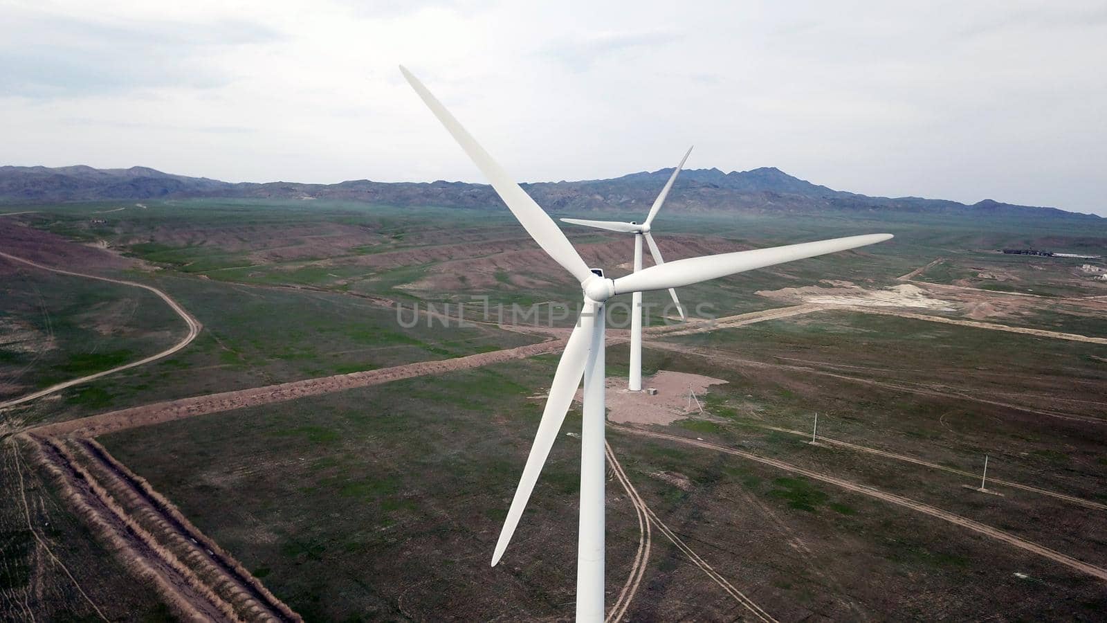 Windmills stand in the middle of green fields. by Passcal