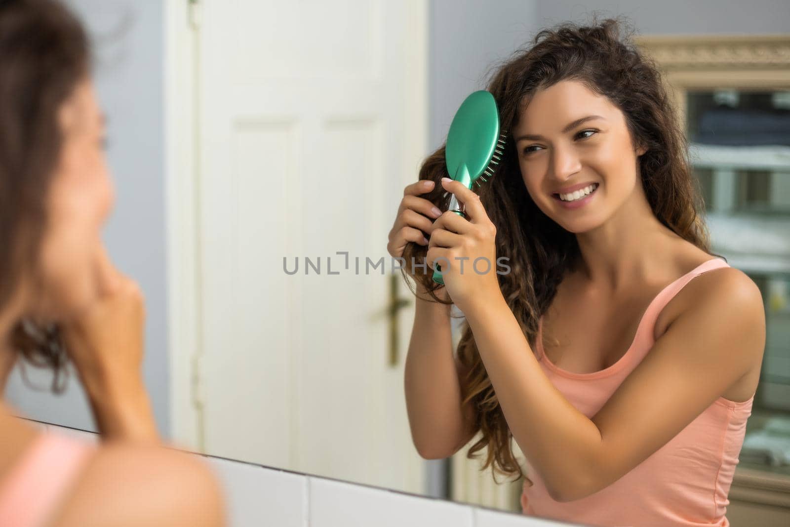 Beautiful woman combing her hair in the bathroom.