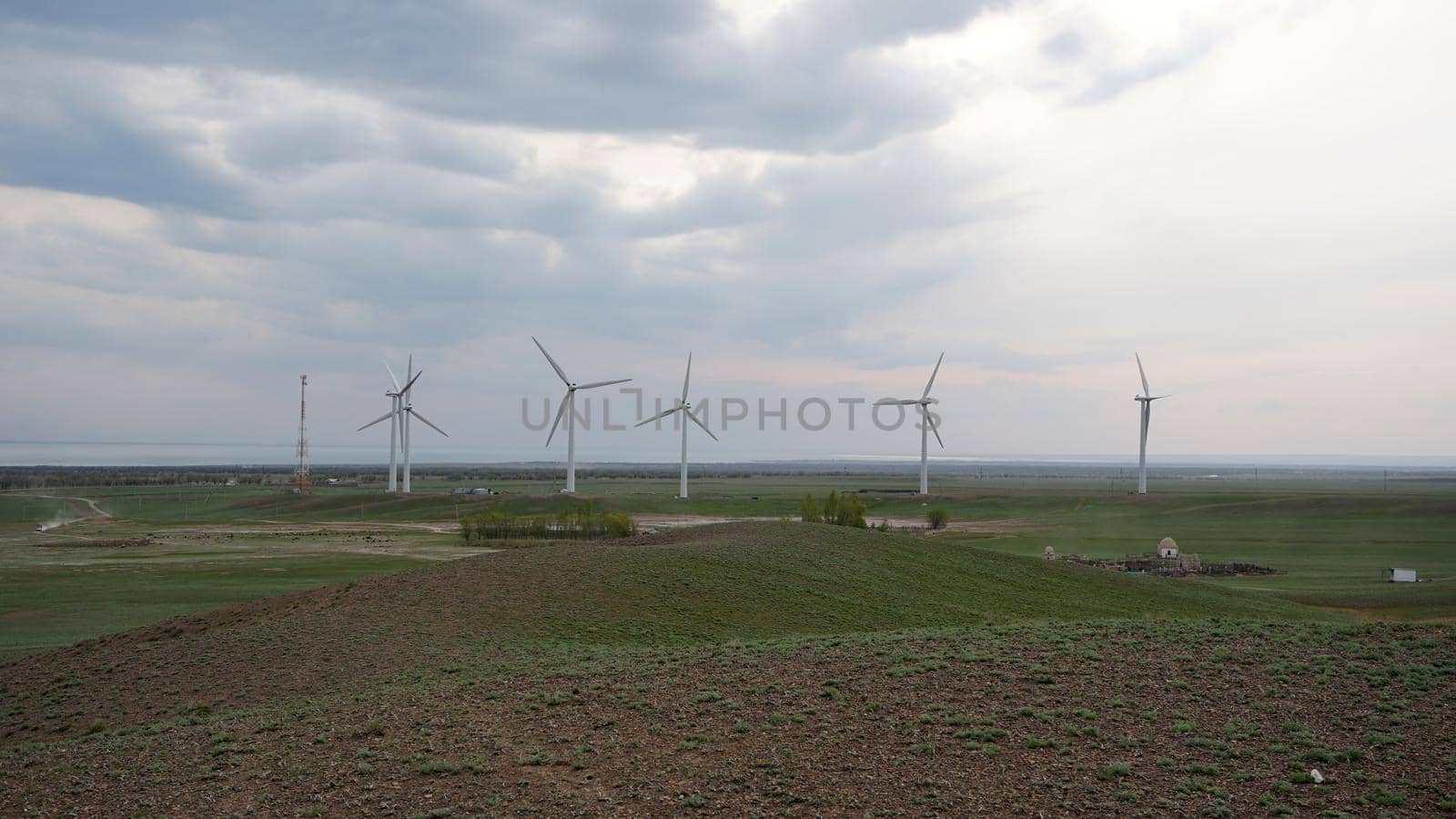 Windmills stand in the middle of green fields. by Passcal