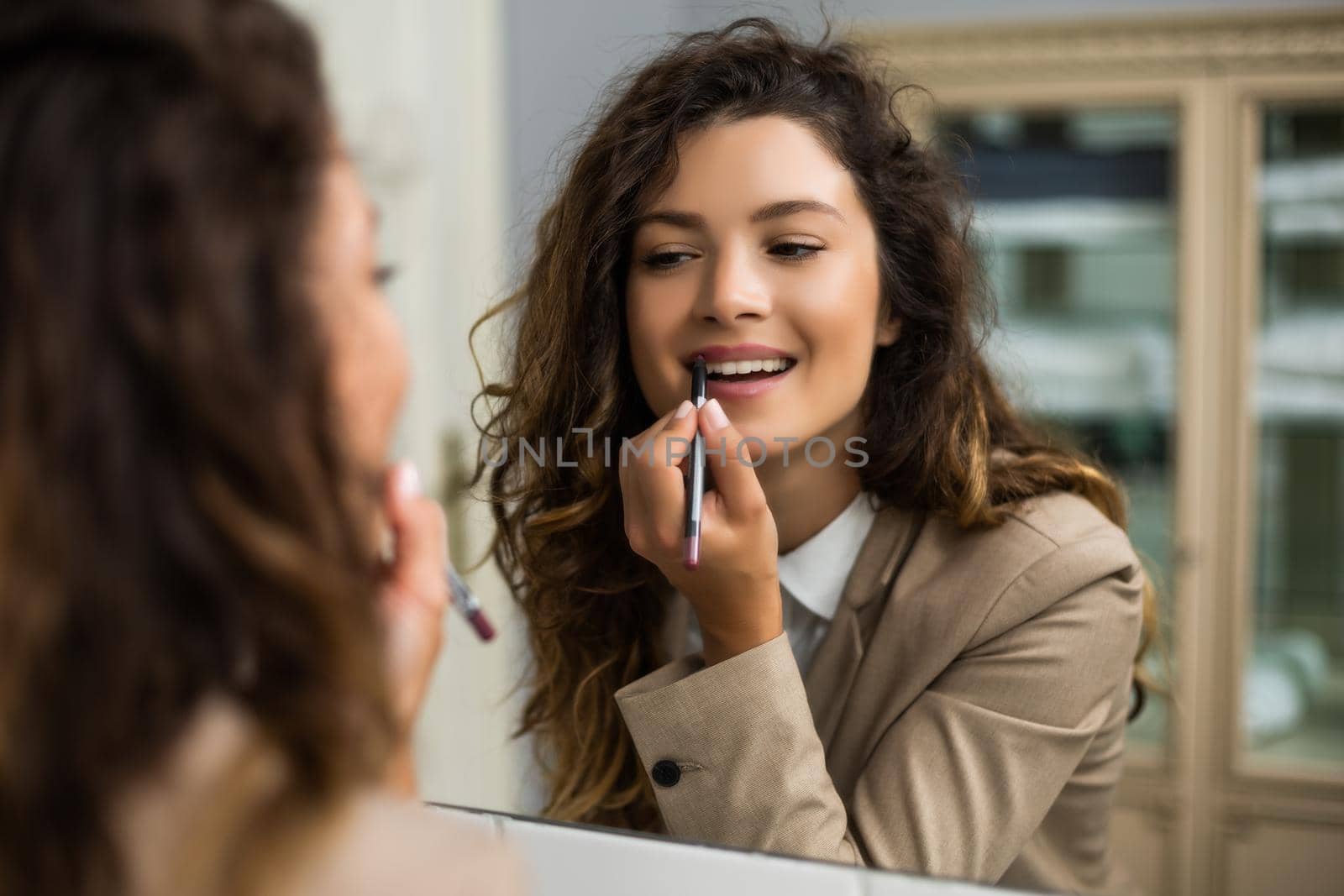 Businesswoman is applying  lipstick by Bazdar