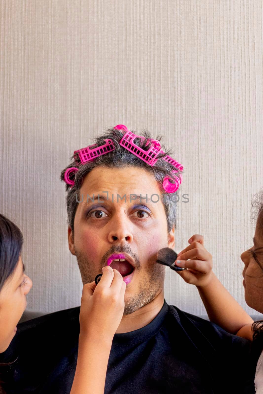 Handsome father is being makeup by the hands of his daughters