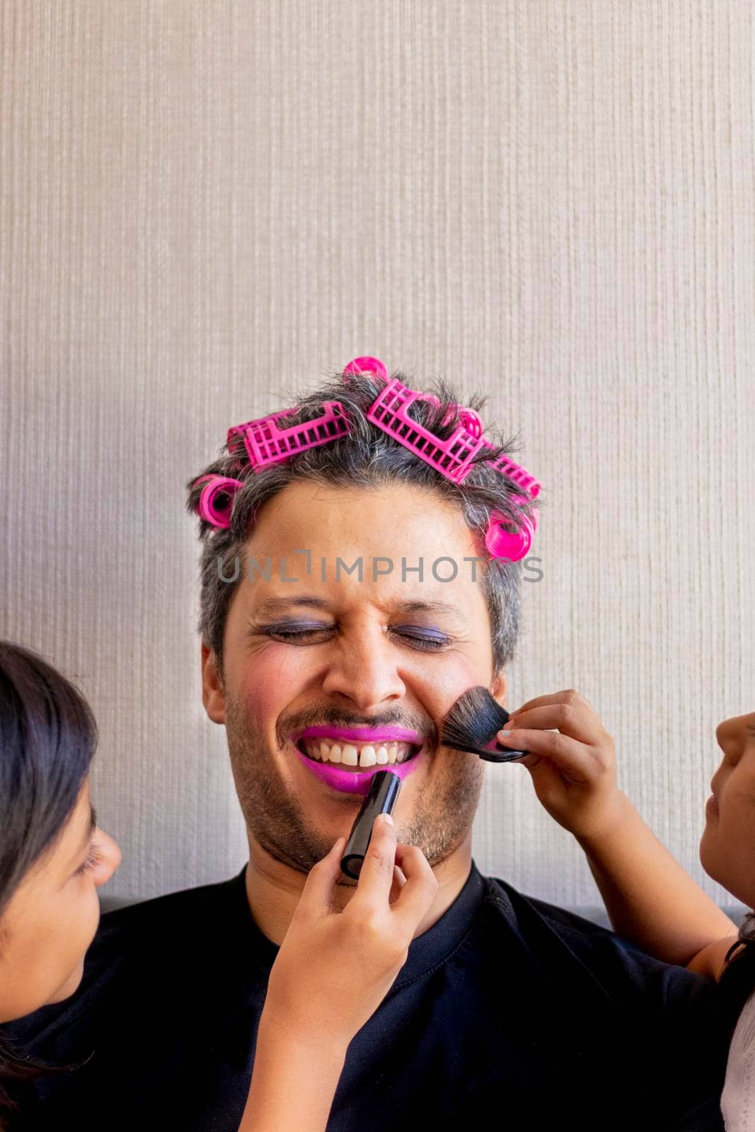 Handsome father is being makeup by the hands of his daughters