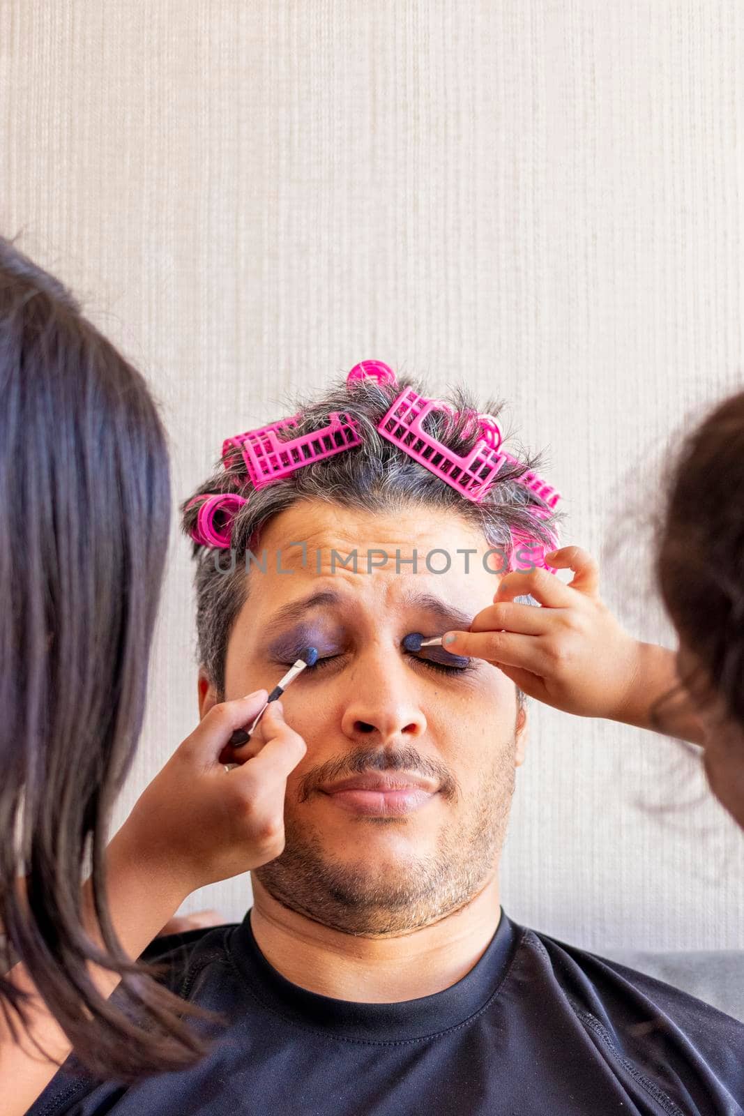 Handsome father is being makeup by the hands of his daughters
