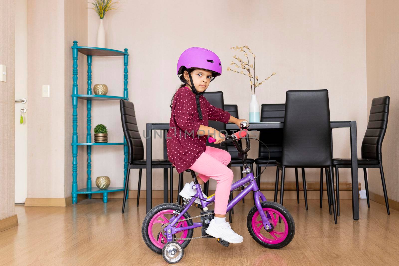 Little girl is riding a bicycle in her living room