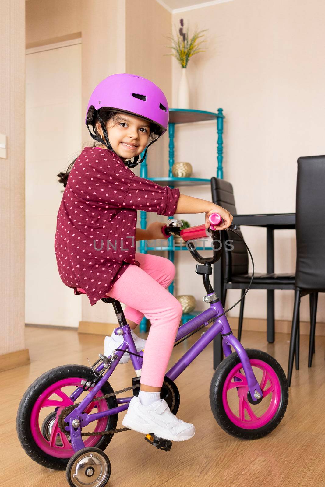 Little girl is riding a bicycle in her living room