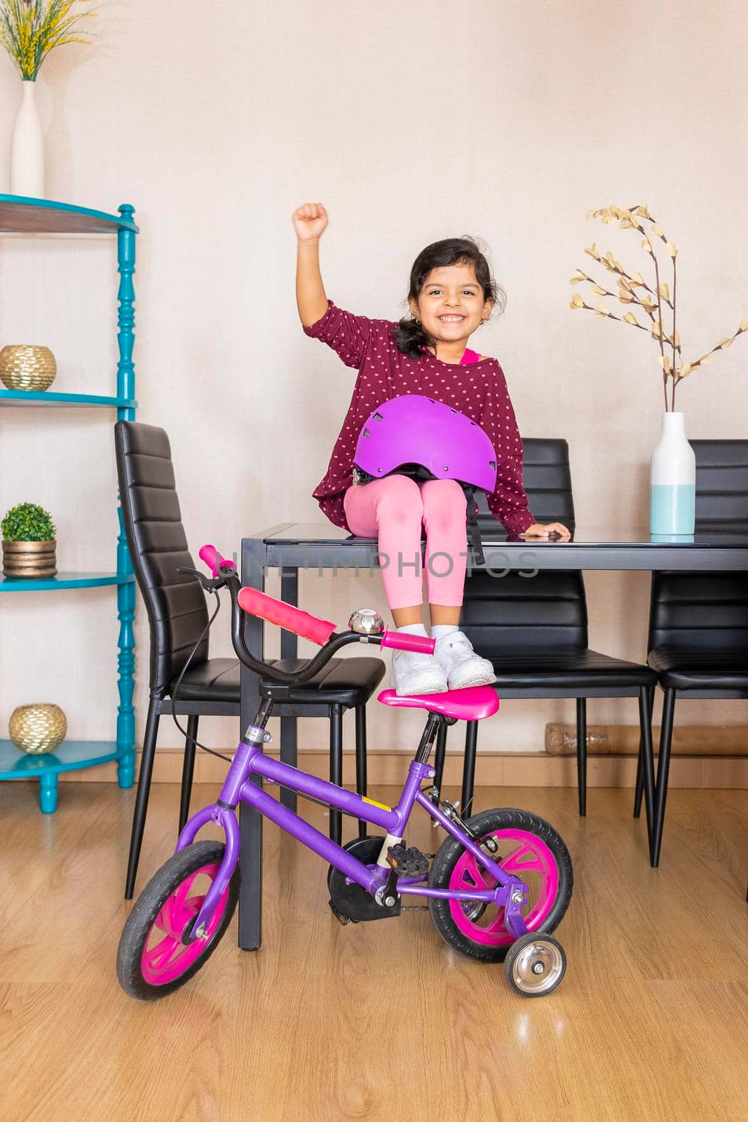 Little girl playing her bicycle in the living room of the apartment during quarantine by eagg13