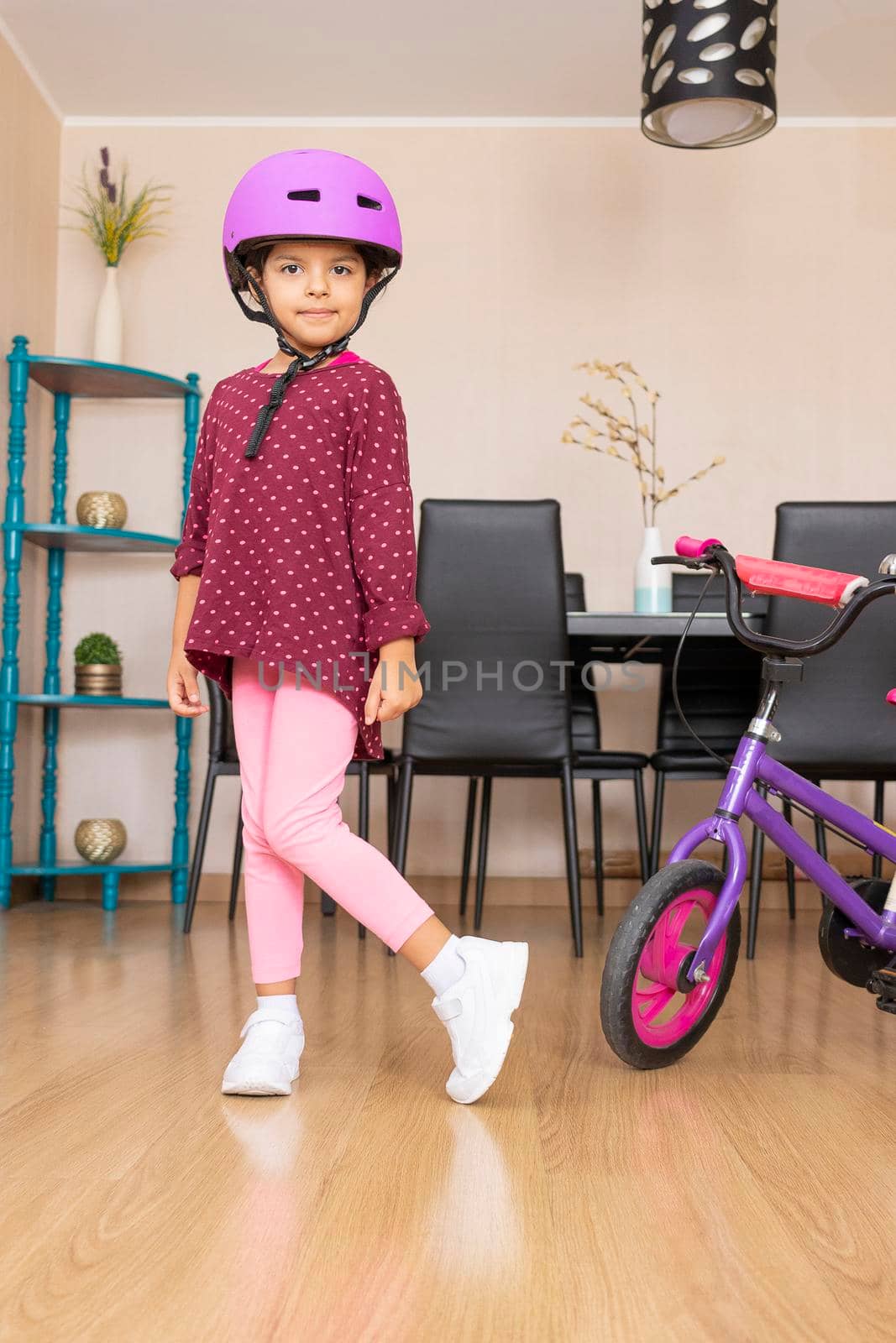Little girl playing her bicycle in the living room of the apartment during quarantine