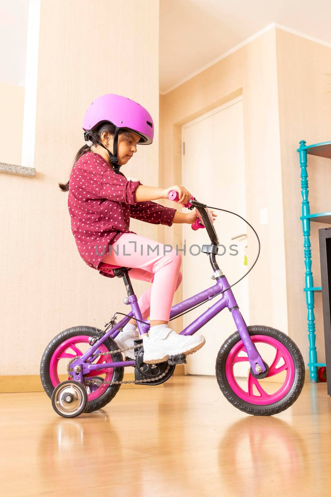 Little girl is riding a bicycle in her living room