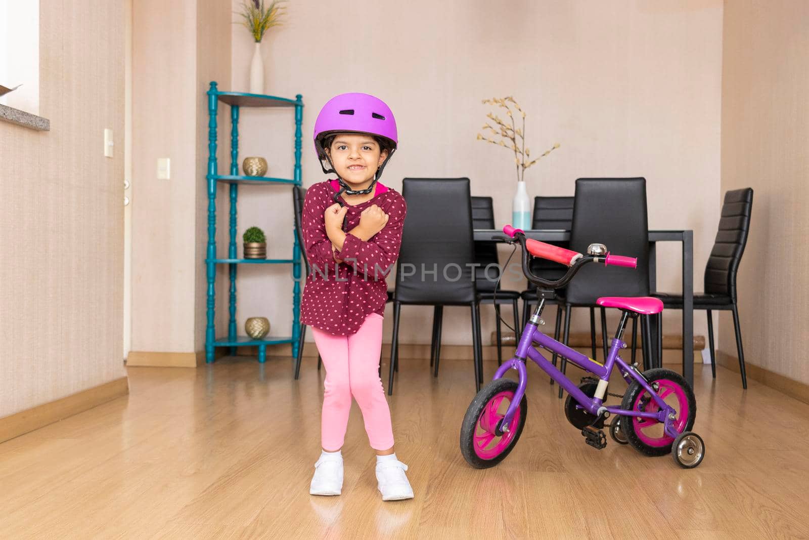 Little girl playing her bicycle in the living room of the apartment during quarantine