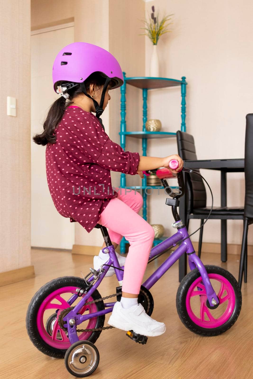 Little girl is riding a bicycle in her living room