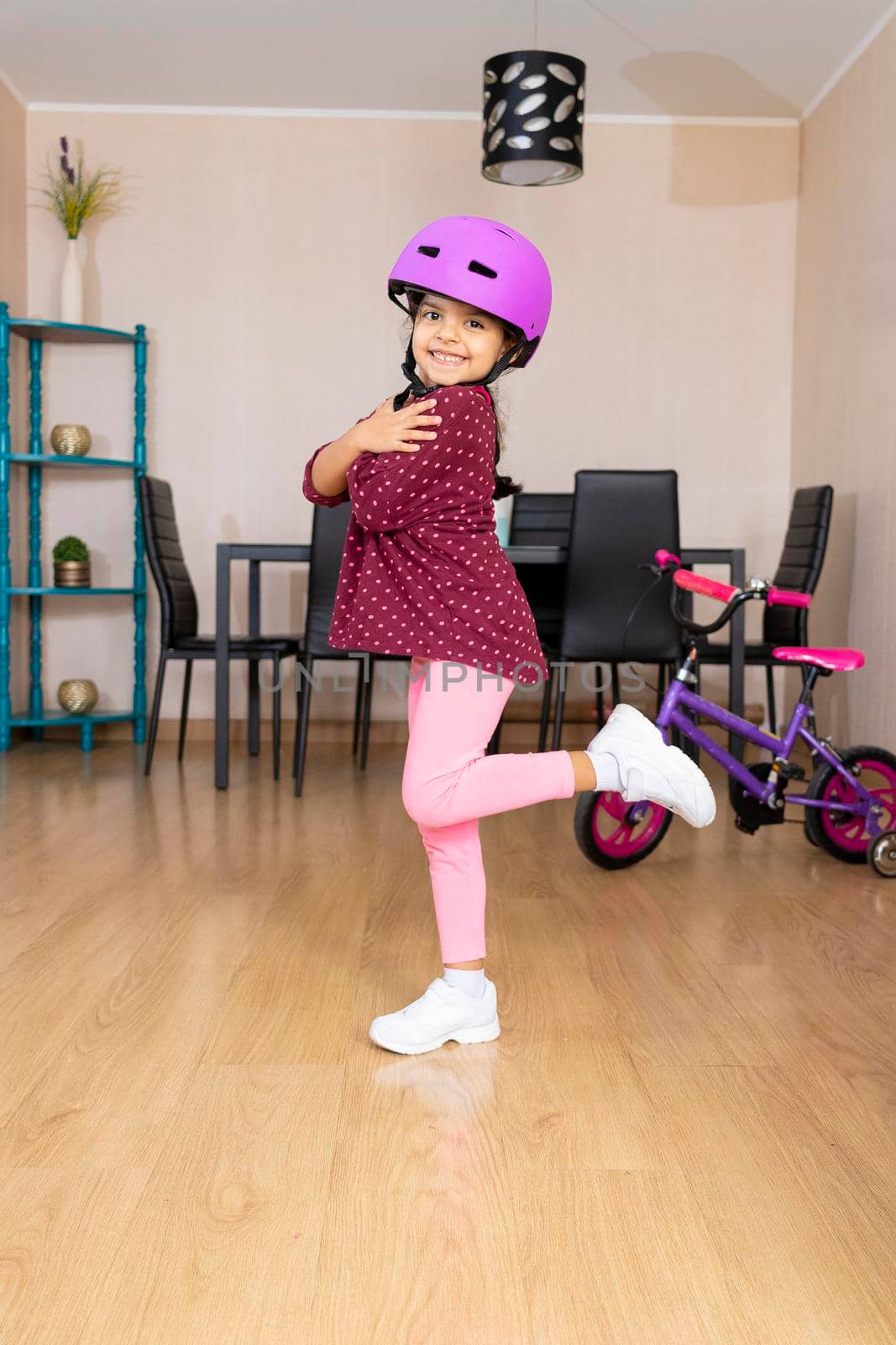 Little girl playing her bicycle in the living room of the apartment during quarantine