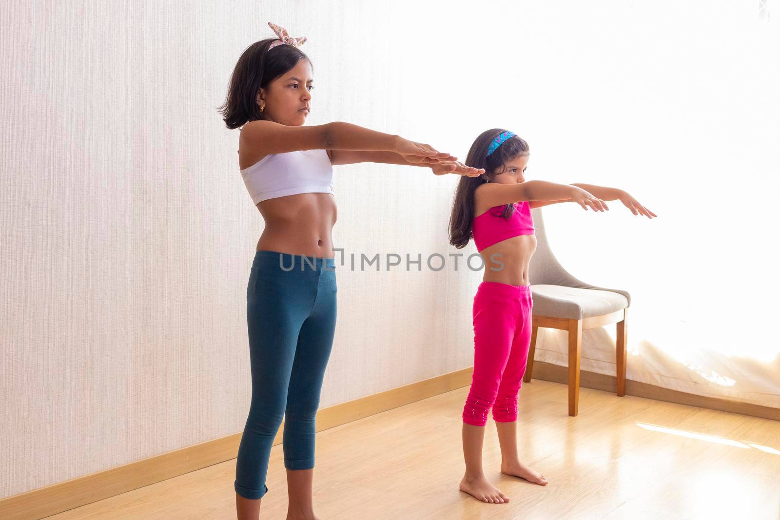 Two little girls are doing exercise routines in the living room at home by eagg13