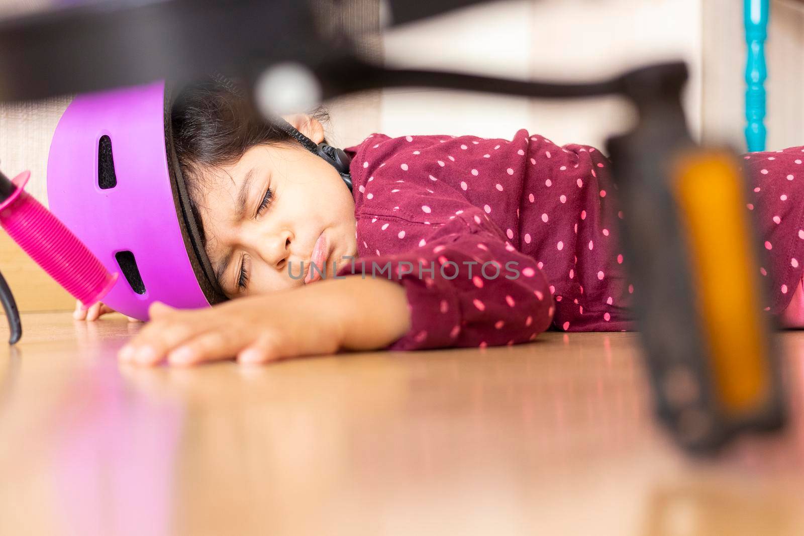 Sad little girl fell to the ground while playing with her bicycle in the house