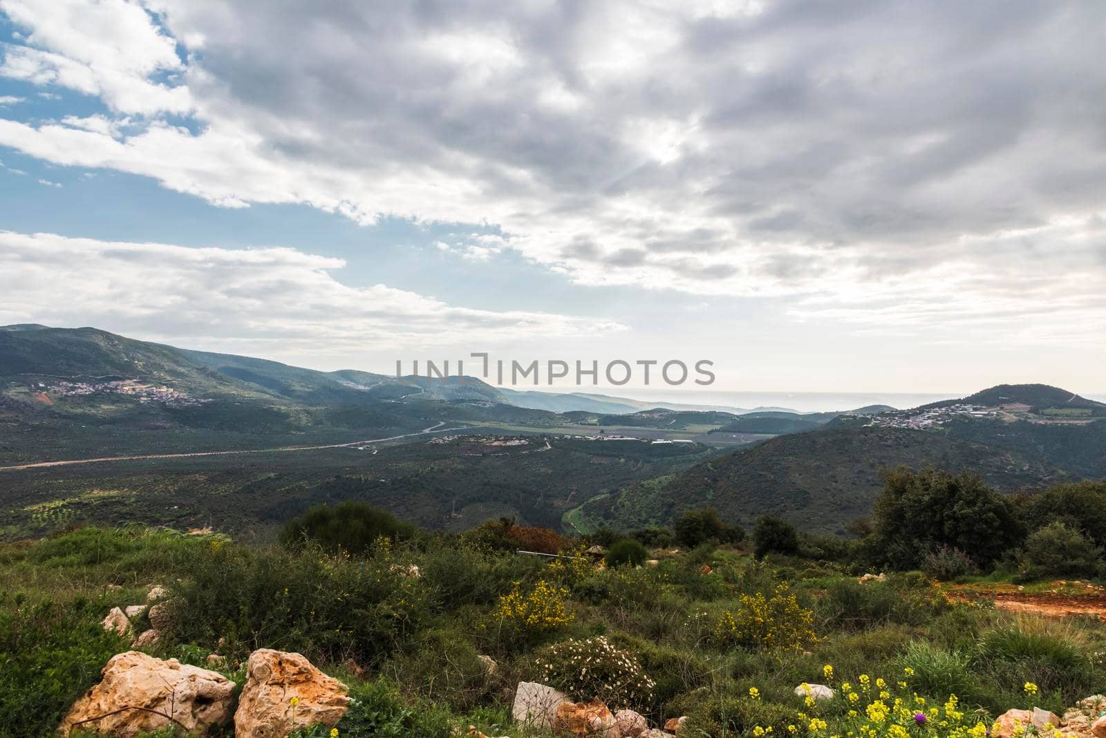 A view of a mountain range and a green valley in the morning at sunrise, against a dramatic back of blue skies and clouds. High quality photo. Travel concept hiking. North District Israel by avirozen