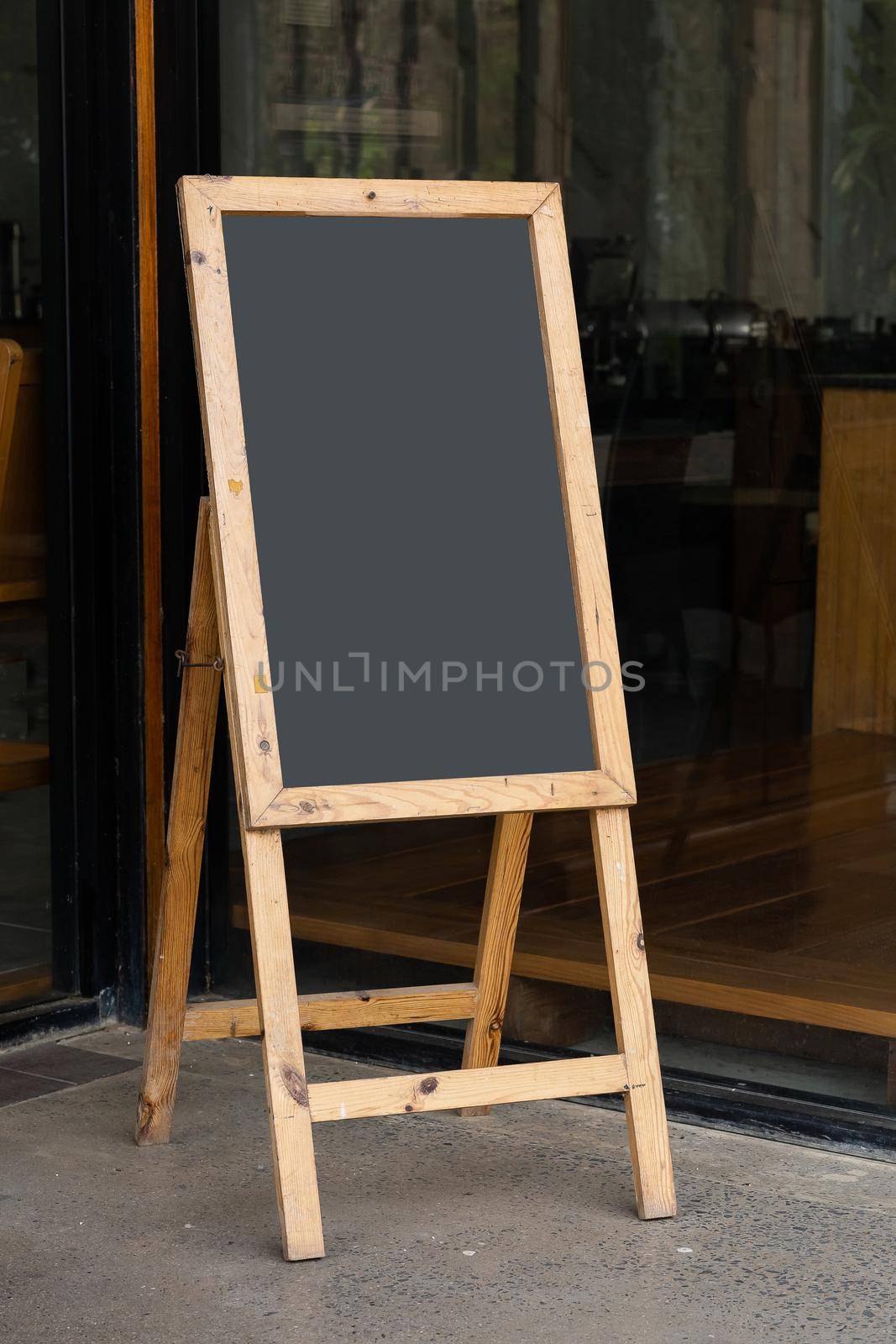 Old blackboard stand in front of restaurant or cafe, empty for advertising display