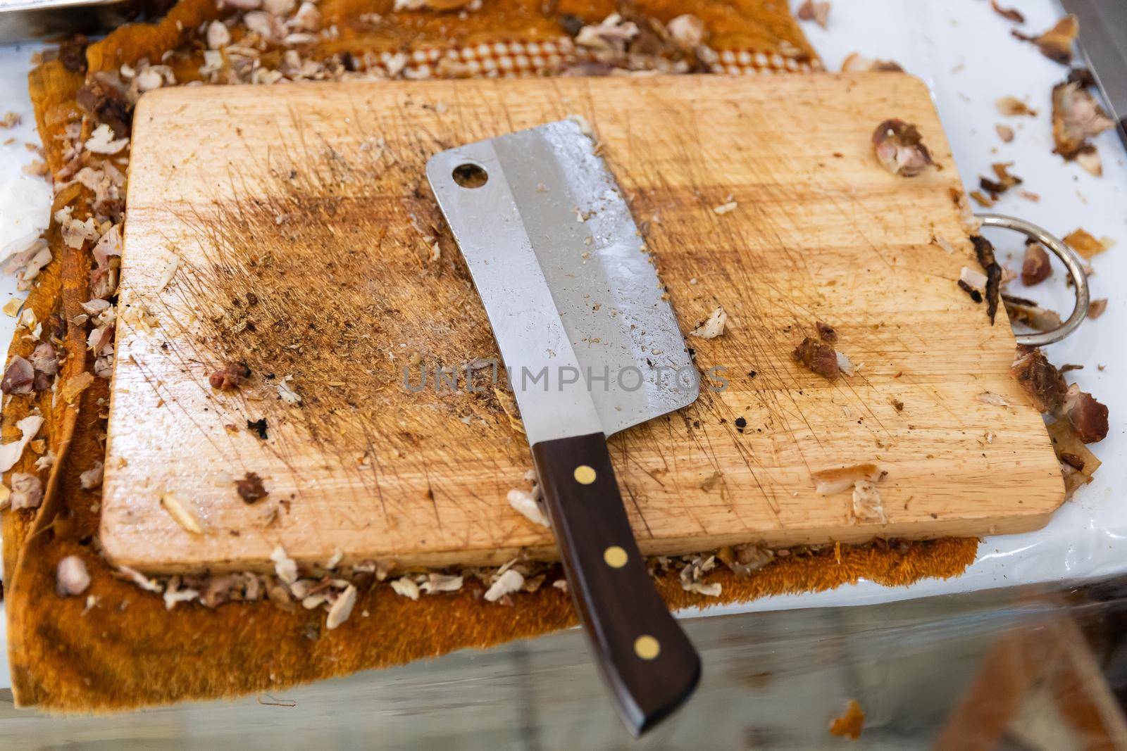 Dirty stainless steel cleaver on wooden chopping board, heavy kitchen knife use in restaurant