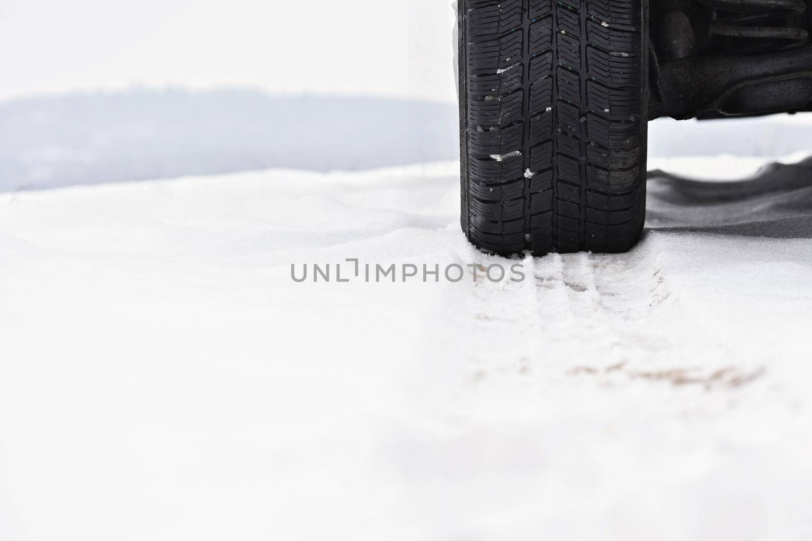 Car in winter. Tire on a snowy road in bad weather.