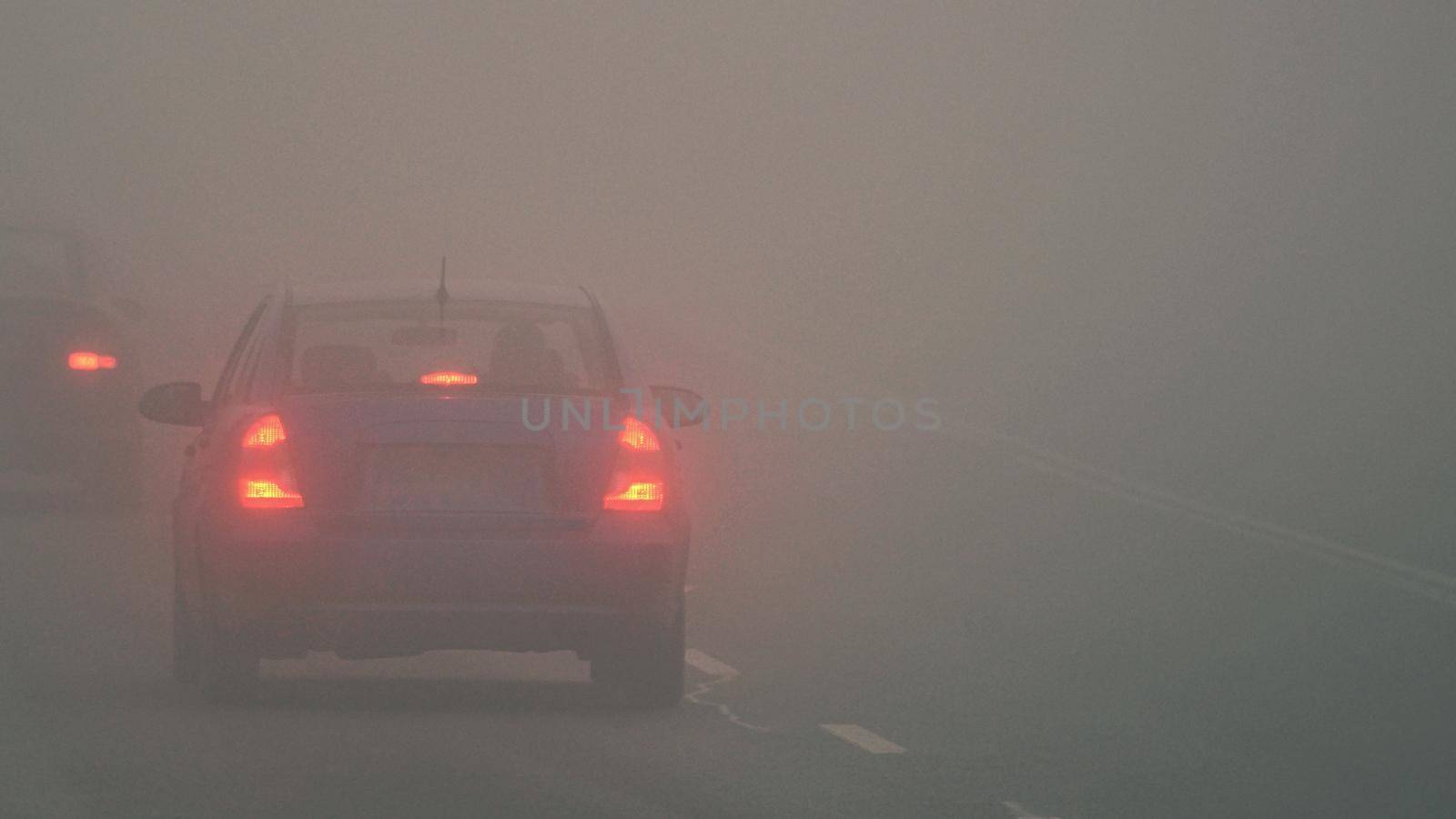 Cars in the fog. Bad winter weather and dangerous automobile traffic on the road. Light vehicles in fog.