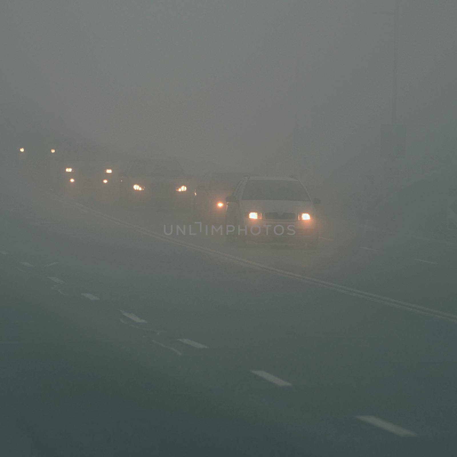 Cars in the fog. Bad winter weather and dangerous automobile traffic on the road. Light vehicles in fog.