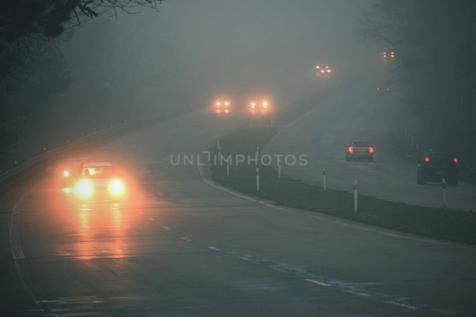 Cars in the fog. Bad winter weather and dangerous automobile traffic on the road. Light vehicles in fog.