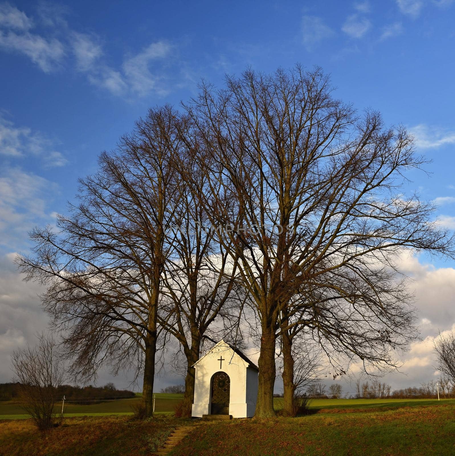 Beautiful little chapel with landscape and trees at sunset. Nebovidy - Czech Republic. by Montypeter