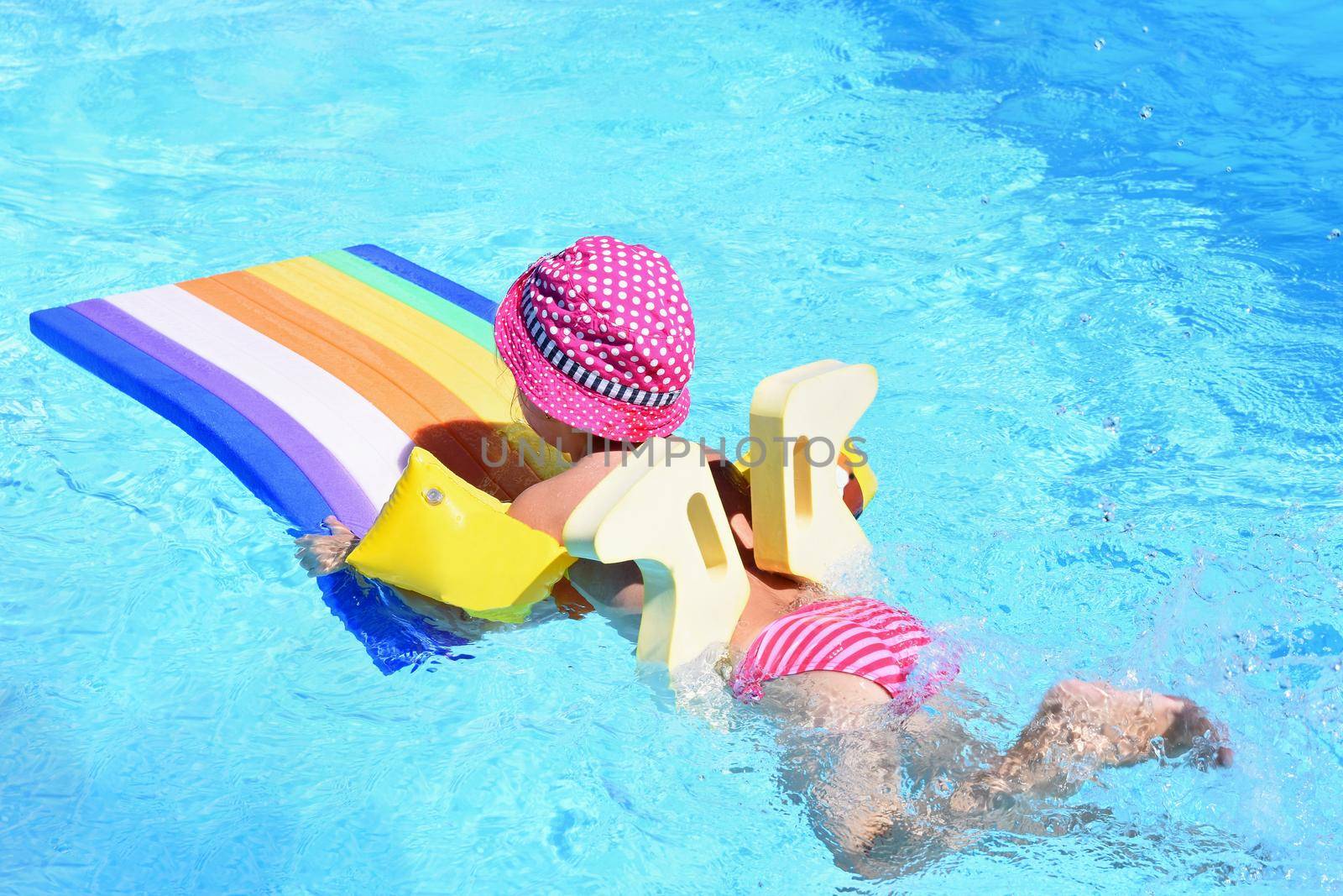 Little baby girl swims on the lilo in water at  hot sunny day. Summer holiday idyllic