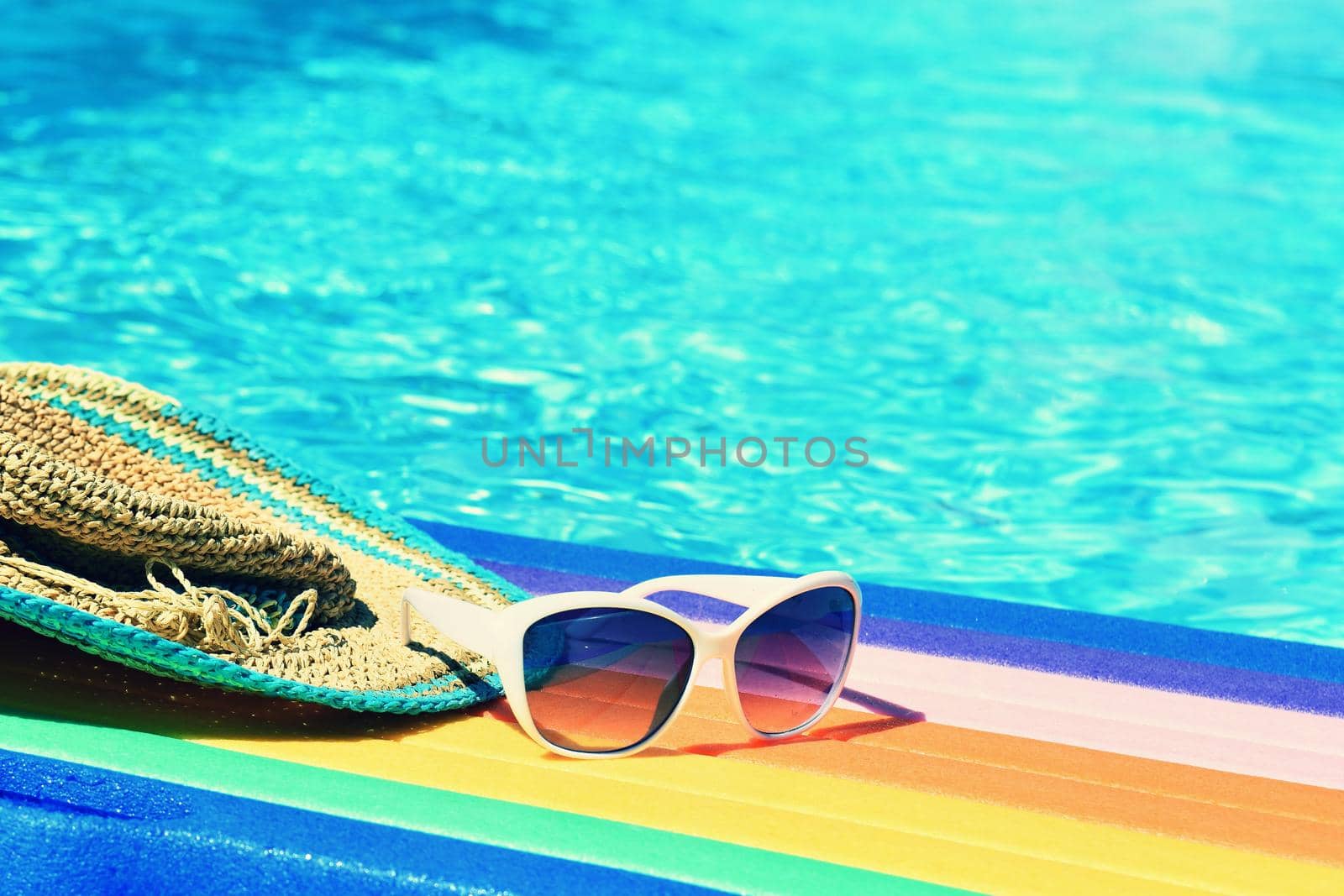 Sunglasses, lilo and hat on the water in hot sunny day. Summer background for traveling and vacation. Holiday idyllic.