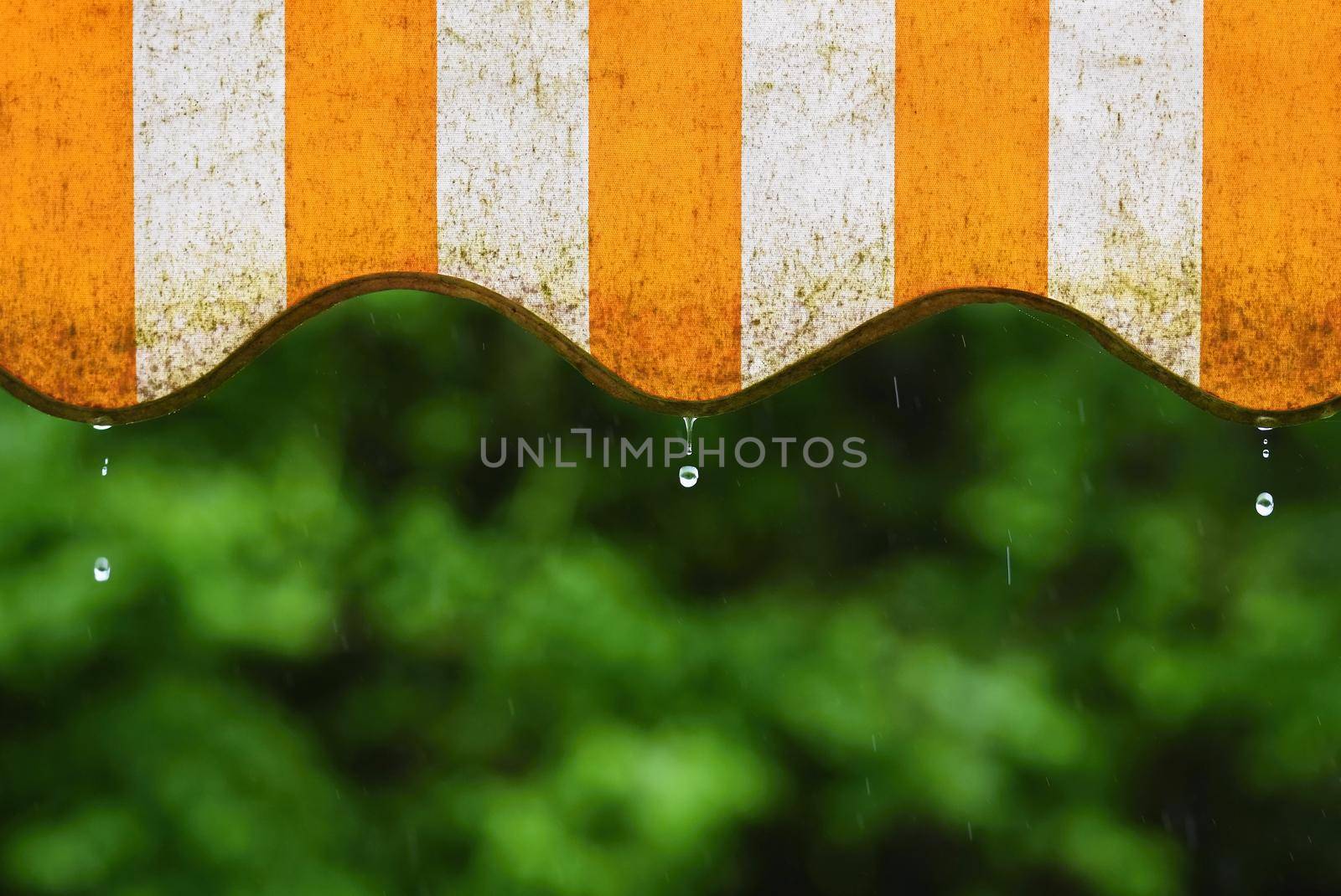 Rain. Awning on a balcony and drops of water on a natural colorful background during a spring day