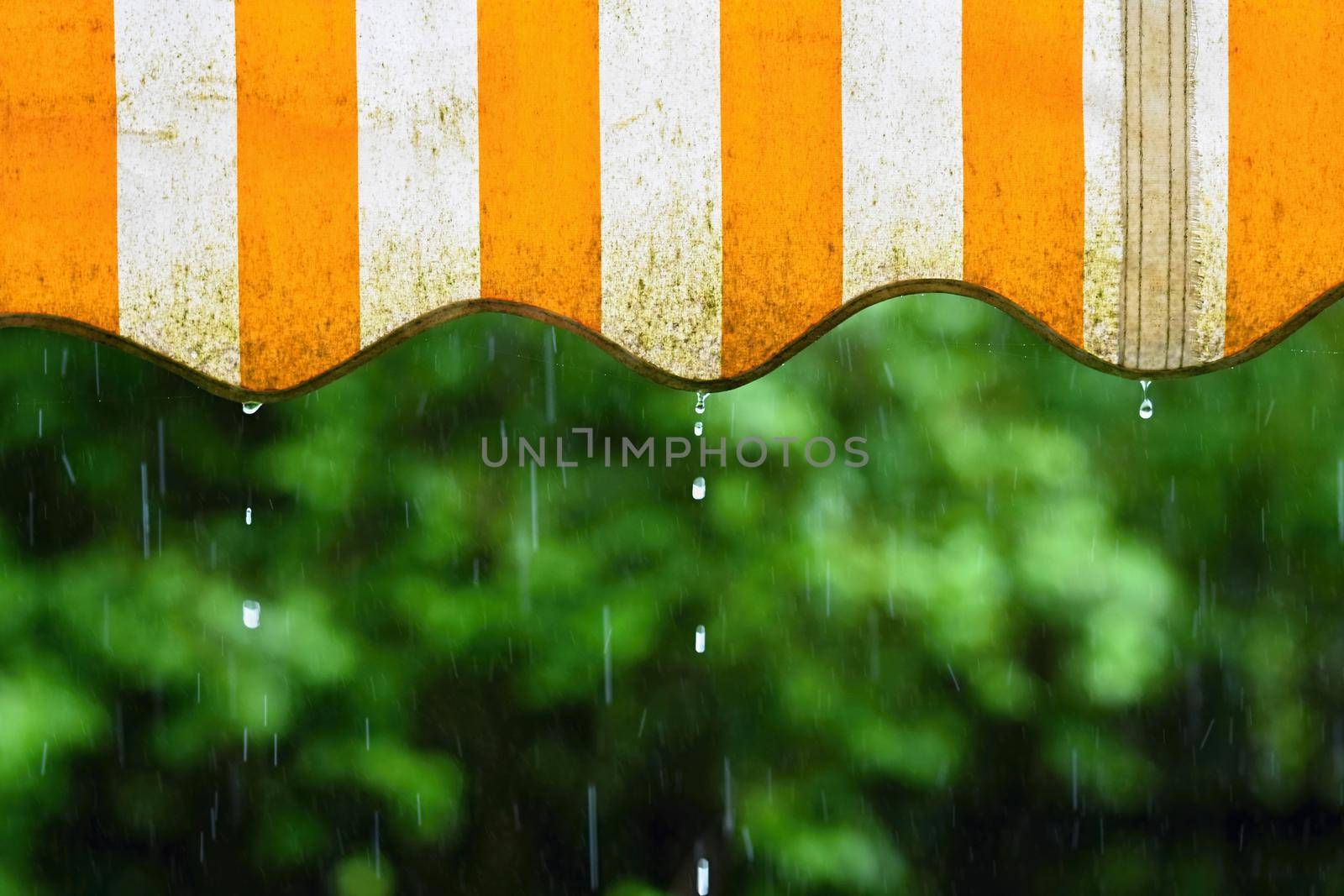 Rain. Awning on a balcony and drops of water on a natural colorful background during a spring day