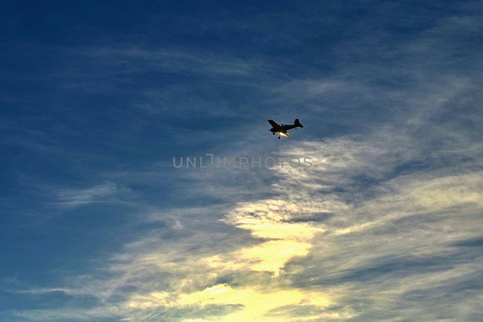 Small airplane on blue sky with clouds and sunset in background by Montypeter