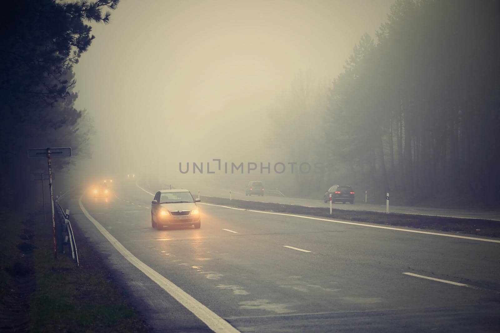 Bad weather driving - foggy hazy country road. Motorway - road traffic. Winter time.