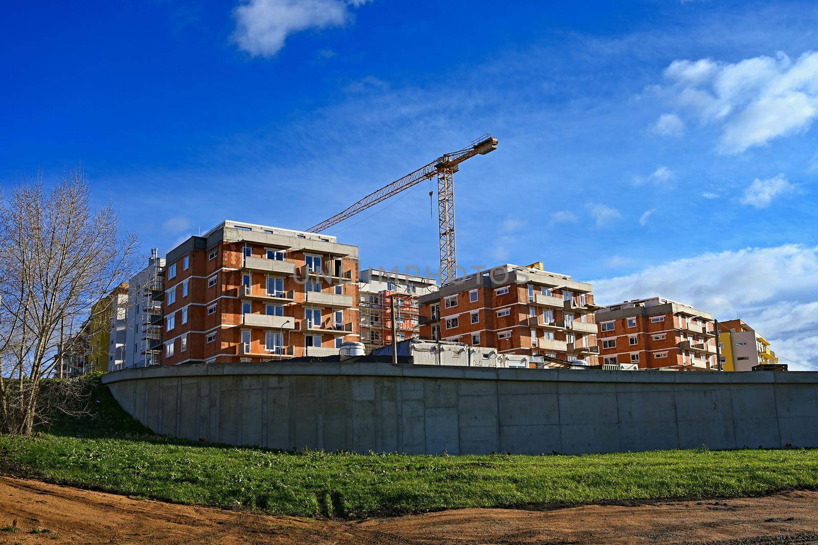 Construction of new homes. Concept for industry. Crane and blue sky with clouds and sun. Building construction site