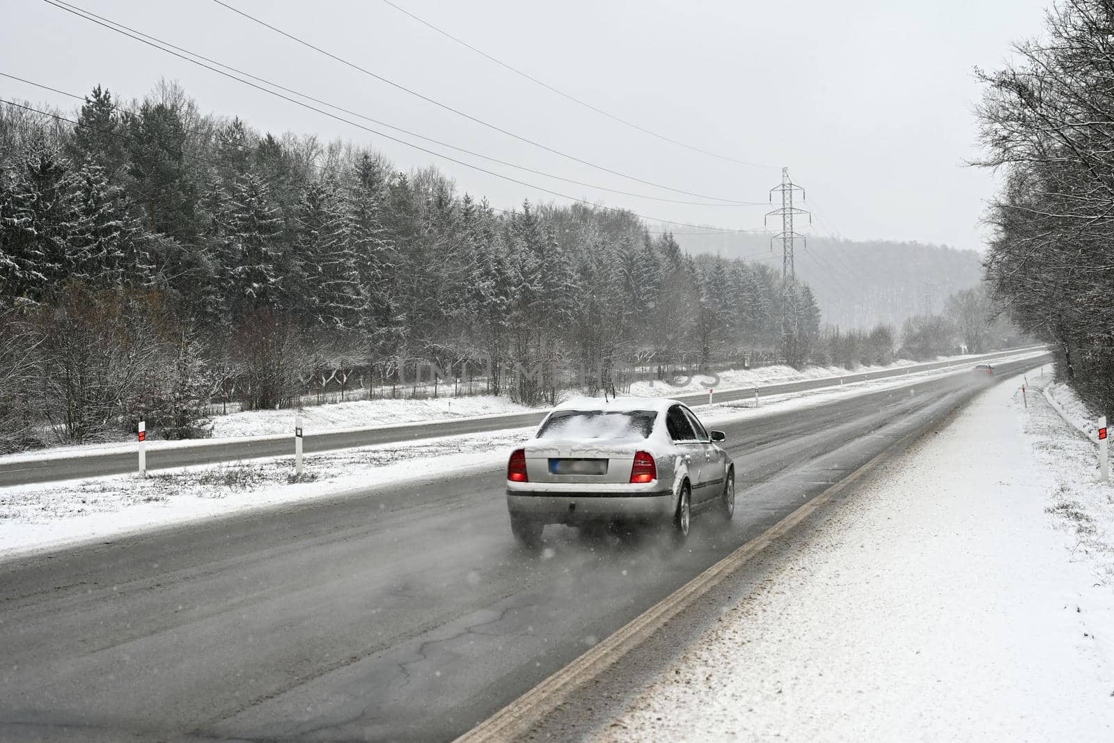 Cars on winter road with snow. Dangerous automobile traffic in bad weather. by Montypeter