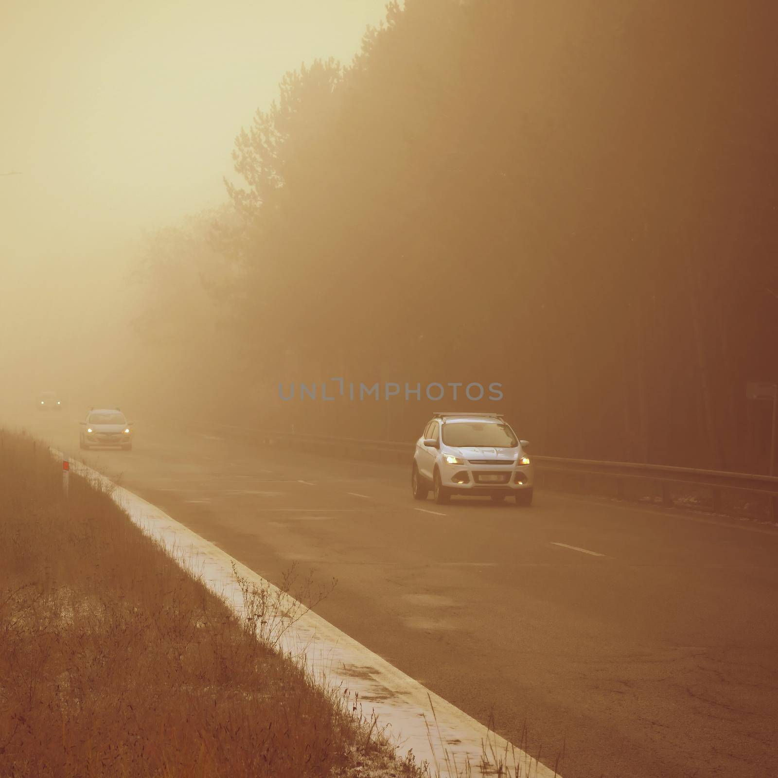 Cars in the fog. Bad winter weather and dangerous automobile traffic on the road. Vehicles in fog. by Montypeter