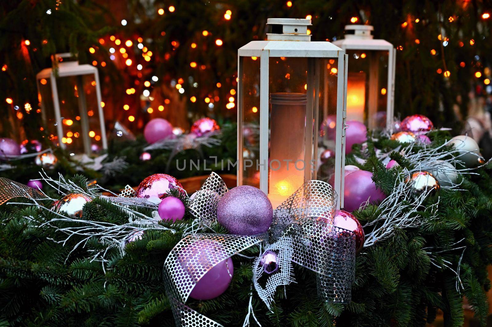 Christmas background. Lanterns with purple ornaments on a Christmas tree. Beautiful blurred abstract colorful lights in the background. Concept for holidays, winter time and a happy new year.