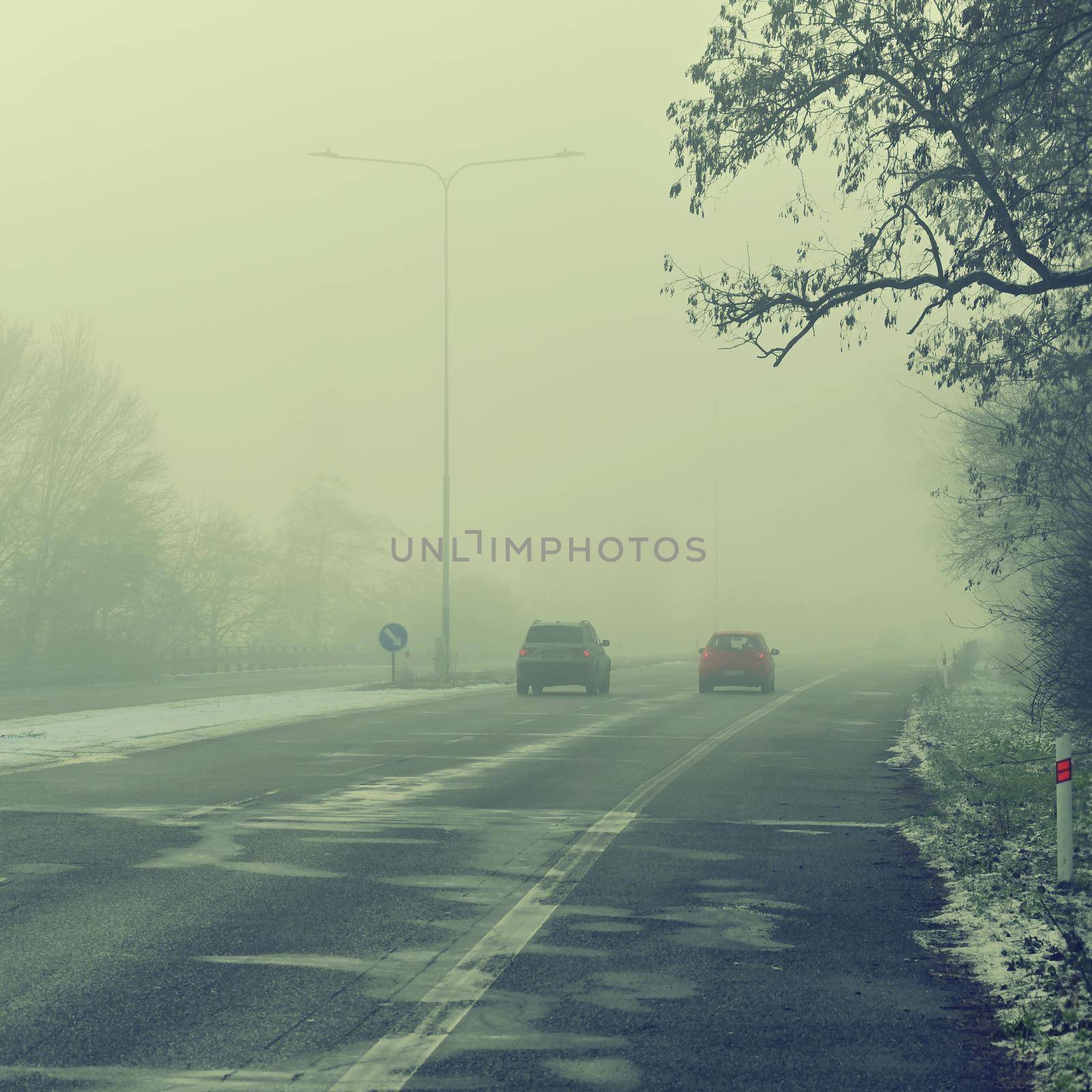 Cars in the fog. Bad winter weather and dangerous automobile traffic on the road. Vehicles in fog. by Montypeter