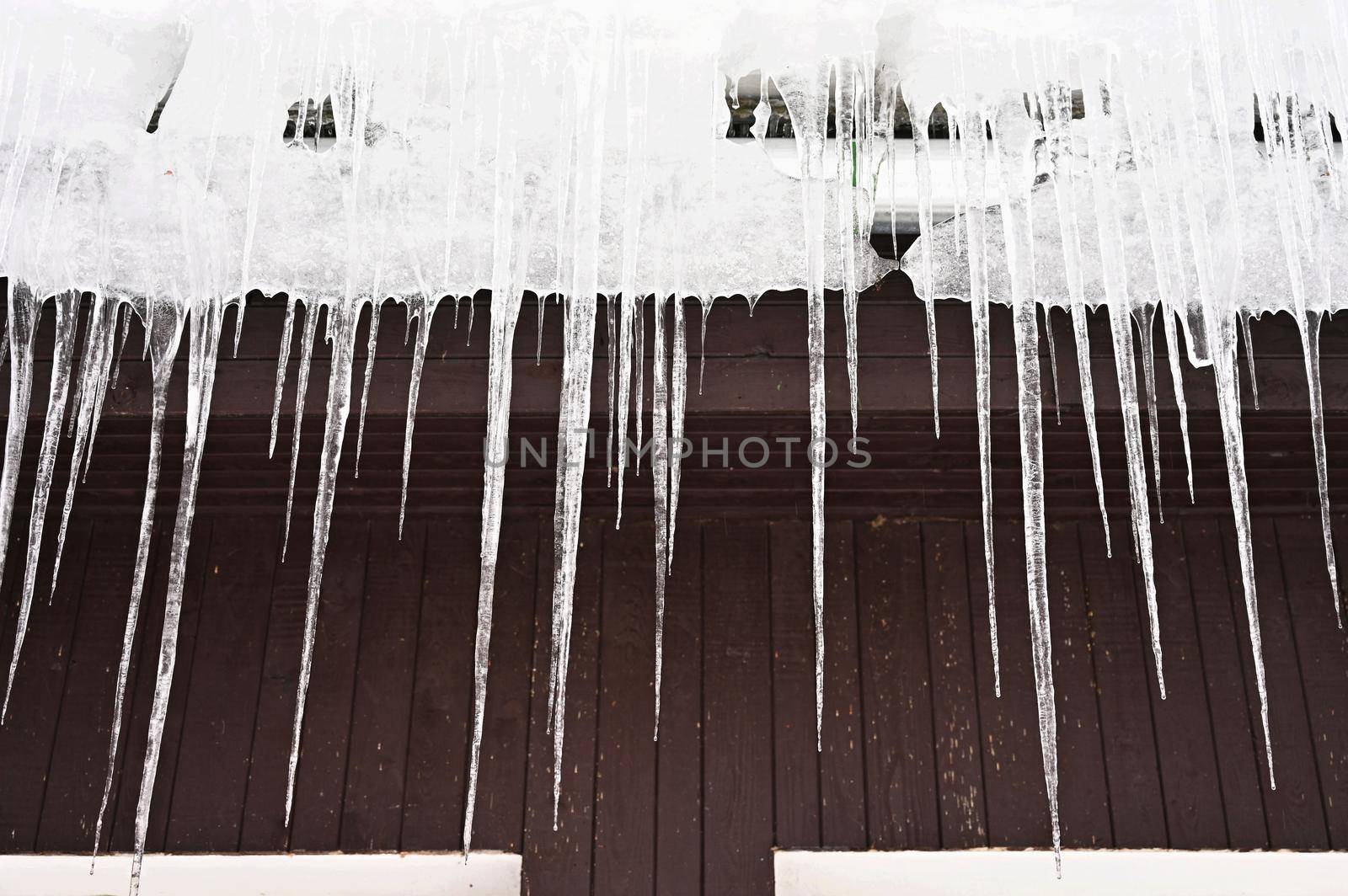Beautiful icicles hanging from the house roof in winter. Concept for winter and frost.