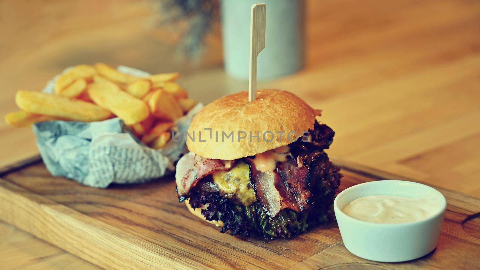 Delicious fresh homemade burger on a wooden table with sauce and French fries.