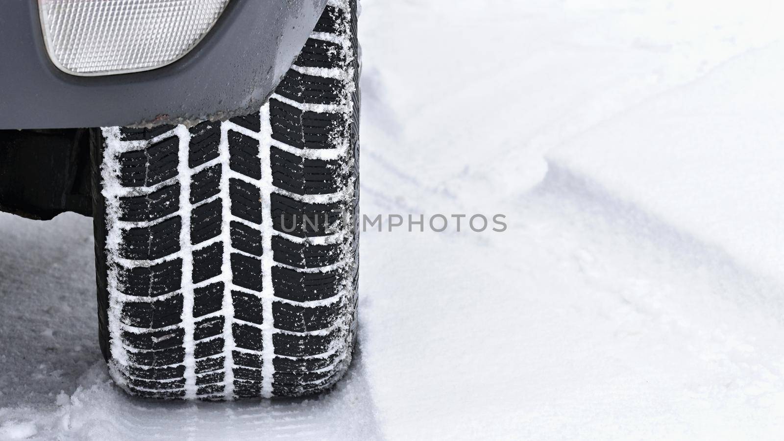 Car in winter. Tire on a snowy road in bad weather.