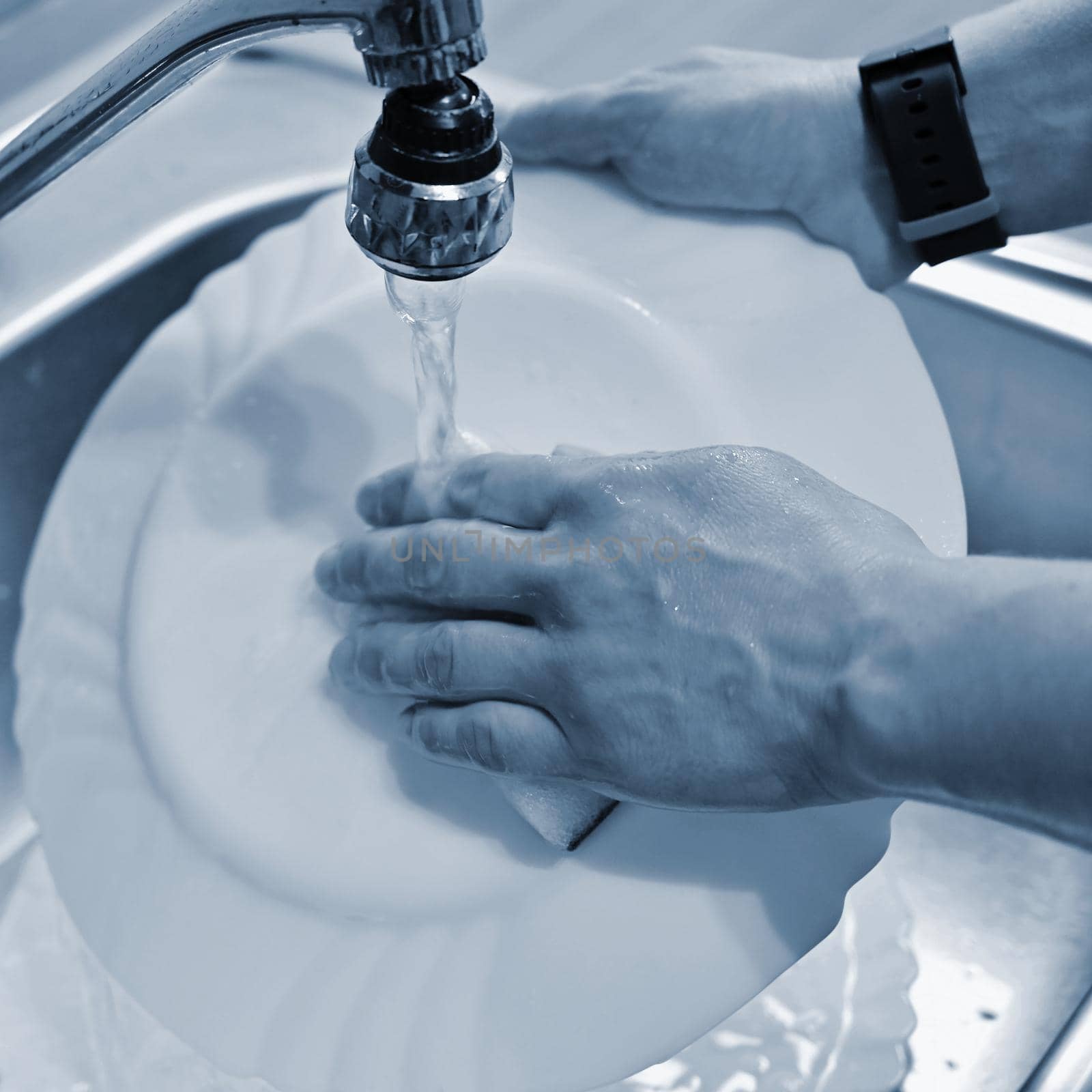 Hand washing dishes. Hand with sponge and sink in kitchen washing dirty dishes - plate.